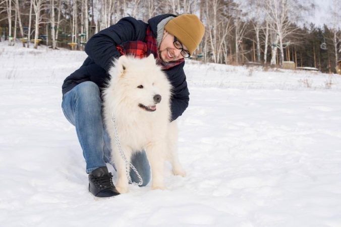 Hombre abrazando un perro blanco en la nieve